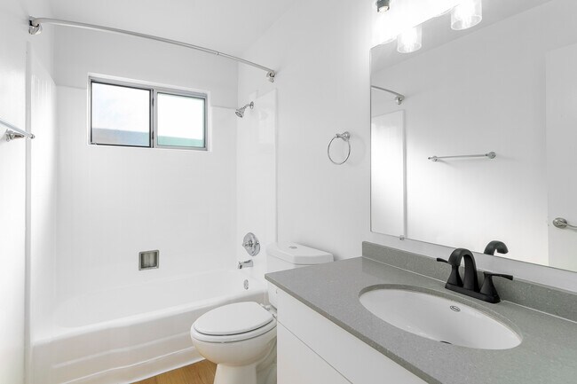 Baño en el pasillo con combinación de bañera y ducha y tocador para guardar cosas.