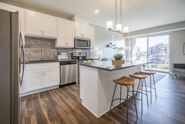 Disfruta de una isla de cocina con iluminación colgante elegante. - Ascend at Woodbury Apartamentos