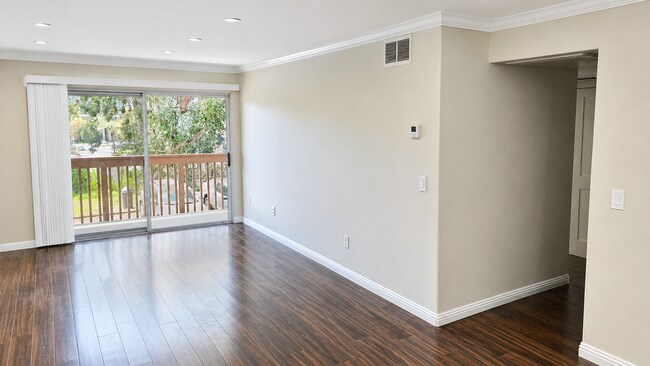 Living Room: Bright, spacious living room with wood-look flooring and recessed lighting.