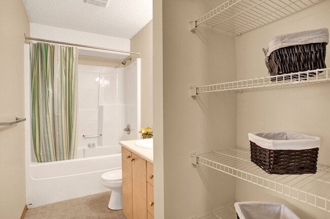 A bathroom with shower, tub, and a mirror above the sink and additional storage - Wellington Manor
