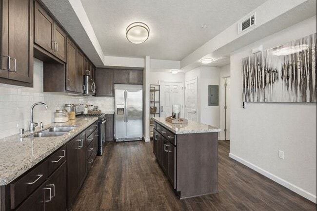 Aspire Apartments Tracy CA A modern kitchen with dark wood cabinets and stainless steel appliances.