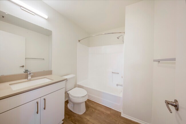 Renovated Package Bath with white cabinetry, grey quartz countertop, and hard surface flooring