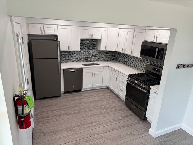 Kitchen with quartz counter tops, gas range, refrigerator/freezer, microwave, and dishwasher - 251 Main St Unit B
