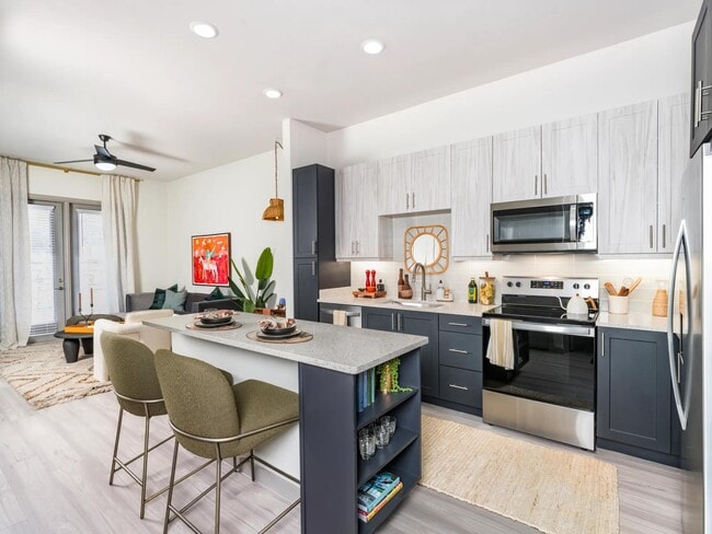 Elevate your culinary skills in our modern kitchen, featuring quartz counter tops, shaker white cabinets with satin pulls, and stainless steel appliances. - Modera EaDo Apartments