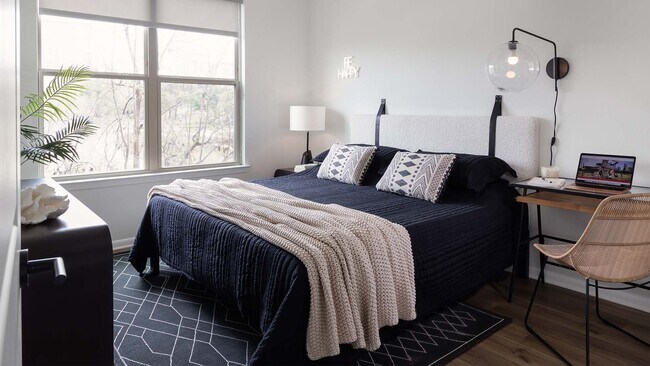 Spacious apartment bedroom with wood-style flooring. - Griffis at The Domain
