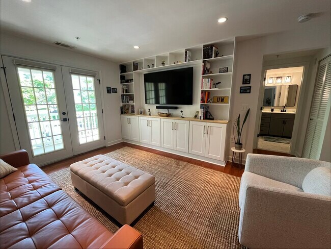 Sala de estar con muebles empotrados a medida y puertas que dan a un balcón privado. - 4079 S Four Mile Run Dr Unidad 301