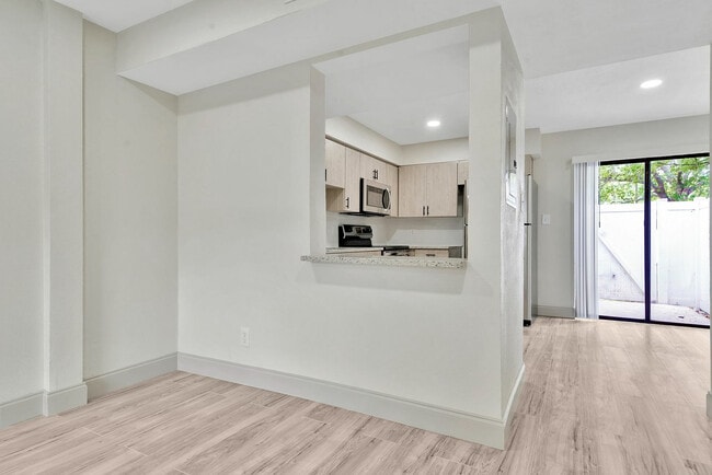 Modern kitchen with sleek cabinetry, granite countertops, and bright open layout leading to a private patio.