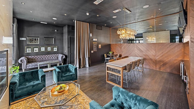 Resident lounge with plush seating, wood style floor, and large TVs.
