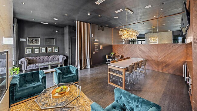 Resident lounge with plush seating, wood style floor, and large TVs. - Griffis Oak Lawn