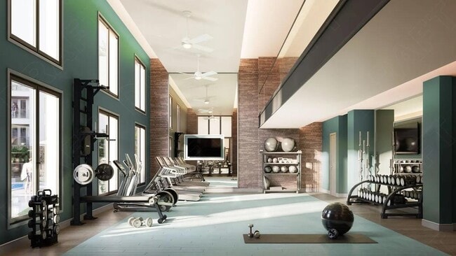 Double-height fitness center with strength and cardio equipment, expansive windows, and dedicated space for training, conditioning, and recovery.