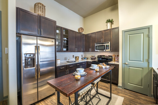 Kitchen with espresso cabinetry, tile backsplash, granite countertops, and stainless steel appliances - Avalon Lakeside Apartments