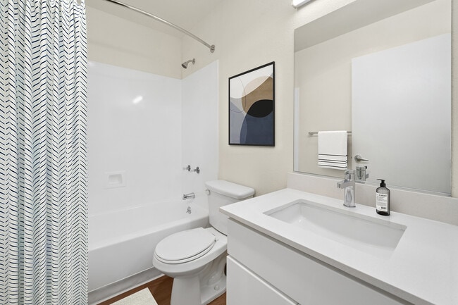 Renovated Package I bath with white cabinetry, white quartz countertops, and hard surface flooring