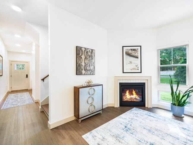 Bright living area with a fireplace available in select homes, large windows, and thoughtful finishes that bring warmth and character indoors. - Modera Weston