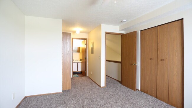 Carpeted bedroom, closet, and attached bathroom of a River Valley apartment home in Lancaster, OH.