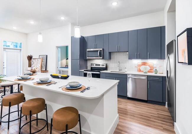 Indulge in culinary delights within Modera Garden Oaks' gourmet kitchens, highlighted by quartz countertops and custom 42-inch cabinetry featuring under-cabinet lighting for both style and practicality. - Modera Garden Oaks Apartments