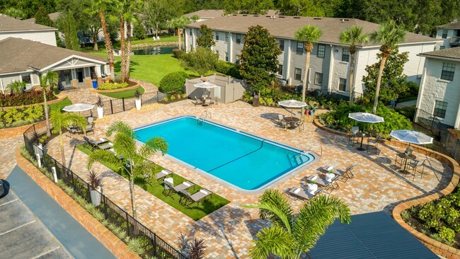 Lounge in luxury on our expansive sundeck, surrounded by lush palm trees and elegant poolside seating. - Ridgemar Commons Apartments