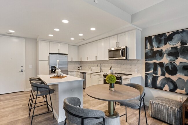 Gourmet Kitchen And Dining Area With White Countertops, Pearl Paneled Cabinets, and Stainless-Steel Appliances - High Street Atlanta Apartments