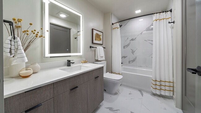 Baño del apartamento con bañera grande, piso de baldosas y espejo de tocador LED. - Griffis Edgemoor