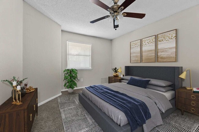 Bedroom with gray upholstered bed, wood nightstands, gold accent lamps, triple framed wall art, and carpet flooring