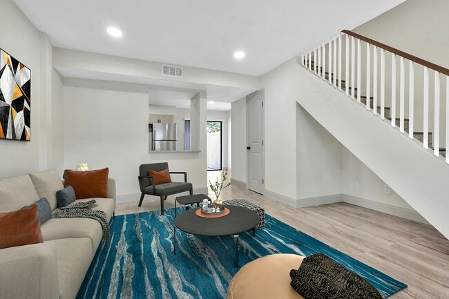 Contemporary living room with elegant staircase, vibrant decor, and an open view to the sleek kitchen.