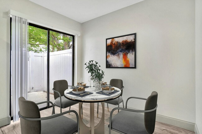 Bright dining area with elegant four-seater table, artistic wall decor, and garden view through large sliding doors.