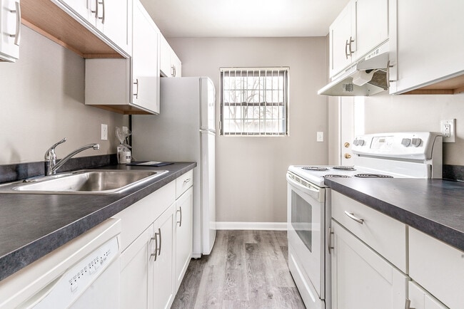 Kitchen with dishwasher, white cabinetry, refrigerator, stove/oven, faux wood flooring, and faux mar