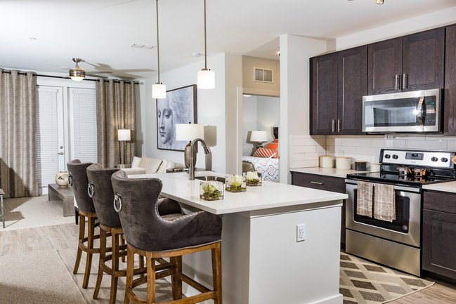 Beautifully decorated model apartment kitchen with barstool seating, shaker style kitchen cabinets, quartz countertops and stainless steel appliances - The Haven at Indigo Square Apartments