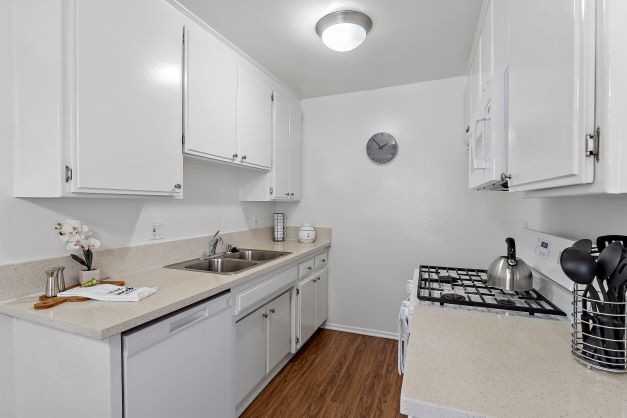 Cocina renovada con pisos de tablones de madera y electrodomésticos de cocina que incluye una estufa a gas, lavaplatos, y un microondas empotrado en Ridgeview Apartment en Northridge