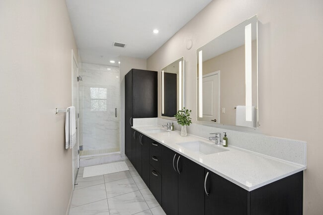 Baño renovado con acabados modernos, gabinetes color espresso, encimeras de cuarzo blanco y pisos de superficie dura.