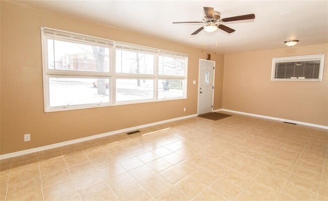 La sala de estar cuenta con mucha luz natural, un ventilador de techo actualizado y pisos de baldosas de fácil mantenimiento. - 2950 N Ritter Ave