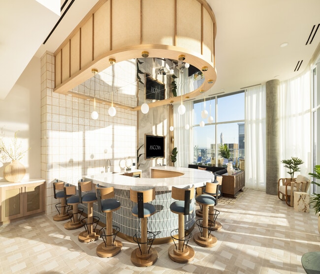 Luxurious modern kitchen with a unique curved island, elegant bar stools, and expansive floor-to-ceiling windows offering stunning city views.