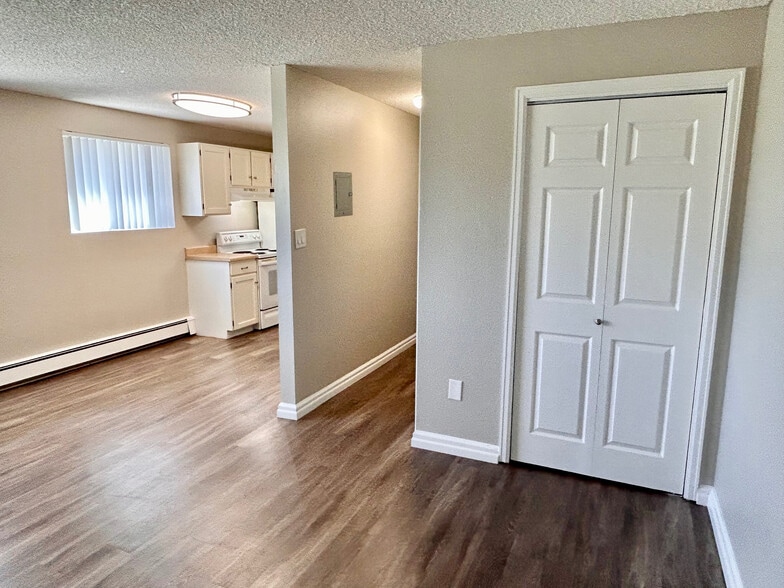 Inviting apartment interior with modern laminate flooring, compact kitchen featuring white cabinetry, and bright natural light.