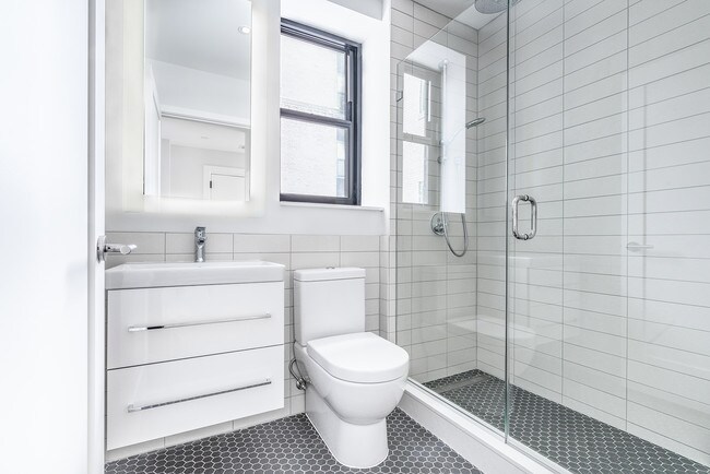 Bright tiled bathrooms with large backlit designer mirror, Hans Grohe chrome fixtures and Villeroy & Boch vanity