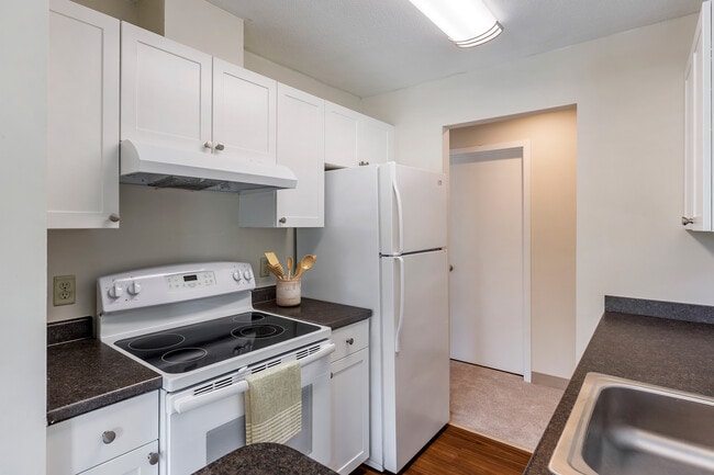 Classic Package I kitchen with white appliances, dark laminate countertops, white cabinetry, and hard surface flooring
