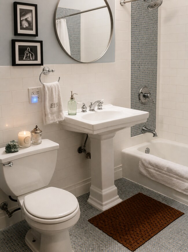 Renovated bathroom with tiled tub and shower, pedestal sink, and heated tile floor. - 3254 15th Ave S Unit 1S
