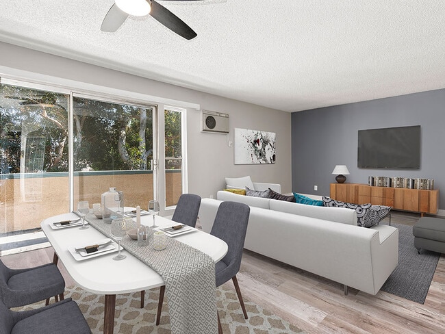 Comedor con suelo de madera noble, ventilador de techo y vistas al salón y al balcón privado.