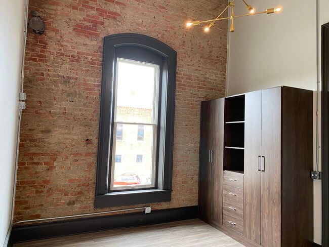 Bedroom with custom wardrobe and brick wall - 102 S Main St Unit Suite 1