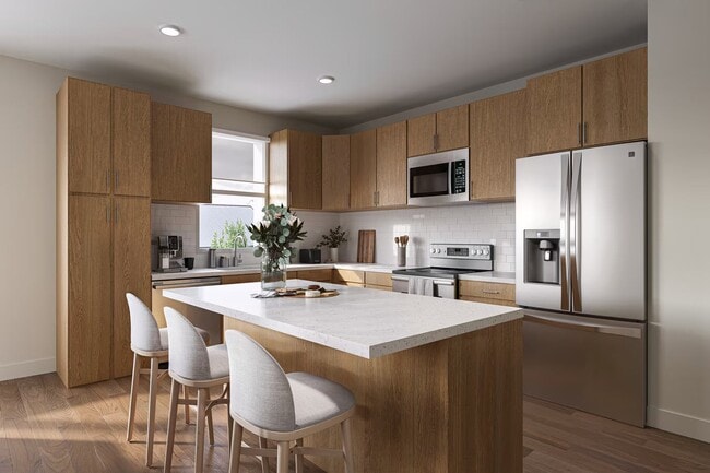 Modern kitchen with wood cabinetry, stainless steel appliances, and a large island.