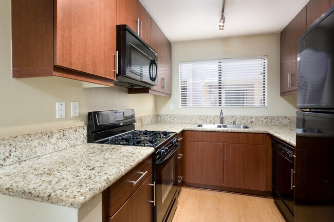 Classic Package I kitchen with chestnut cabinetry, beige speckled granite countertops, black appliances, and hard surface flooring