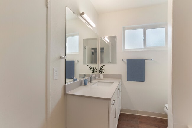 Renovated Package I bath with white cabinetry, beige granite countertops, and hard surface flooring