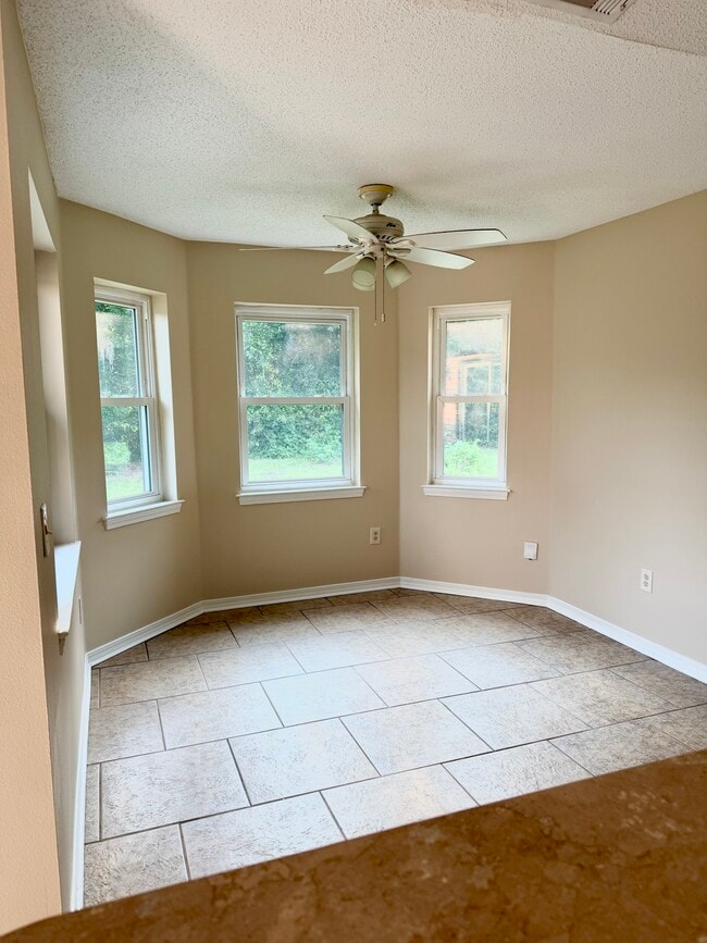 Spacious room with ceiling fan and large bay window overlooking the yard - 6281 Hunters Ridge Dr