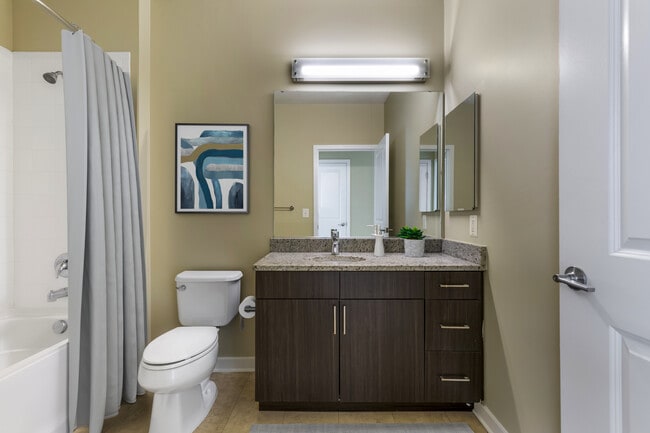 Upgraded bath with espresso cabinetry, grey speckled granite countertops, and hard surface flooring