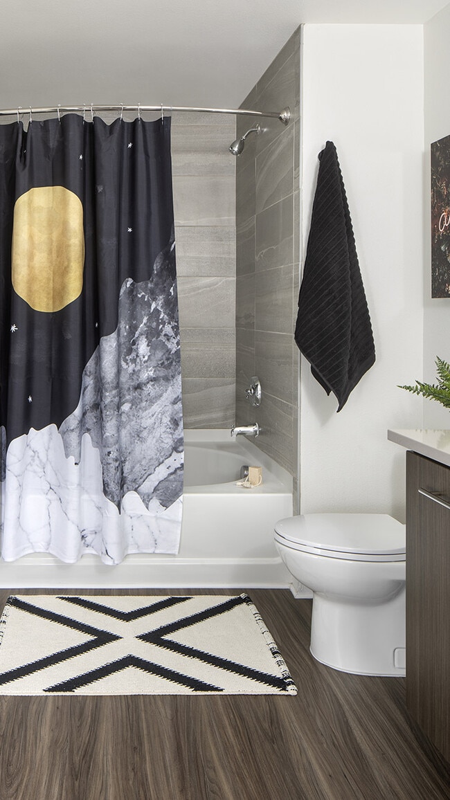 Apartment bathroom with large soaking tub and wood-style flooring.