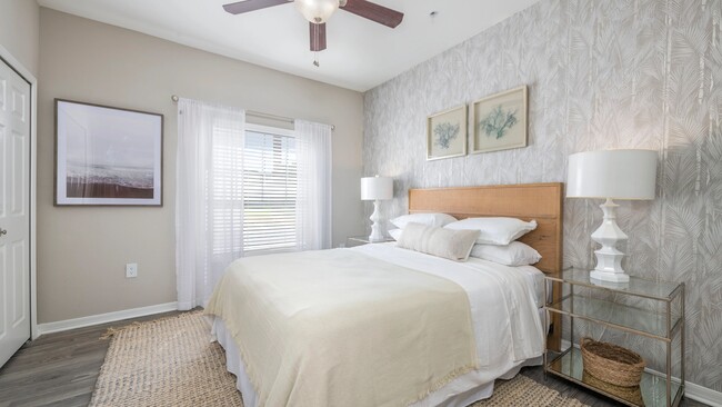 Disfrute del lujo en nuestro espacioso dormitorio principal, decorado con pisos estilo madera y un majestuoso ventilador de techo apto para la realeza. Relájese con estilo y comodidad. - Banyan Bay