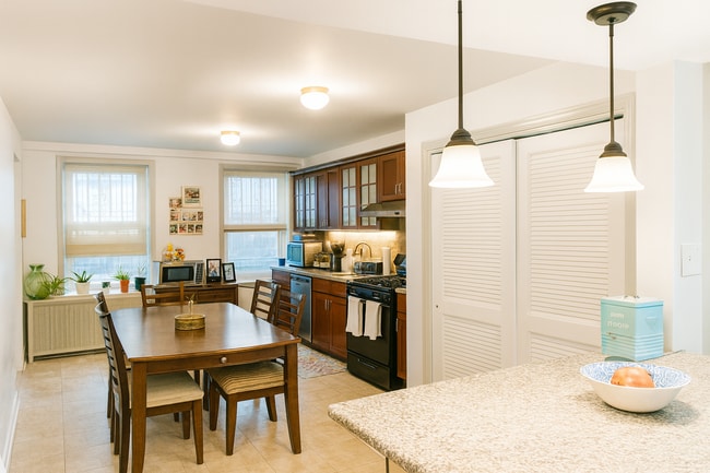 Modern kitchen featuring a vented exhaust hood, built-in dishwasher, and generous cabinet space - 56 Jefferson Ave Unit #1