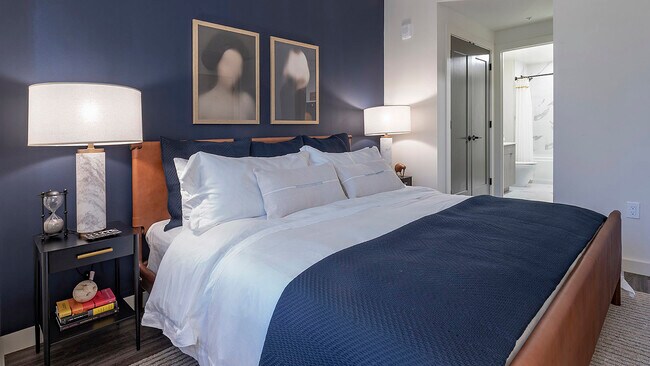 Spacious apartment bedroom with attached bathroom and wood-style flooring.