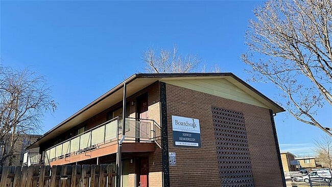Charming newly remodeled brick apartment building with modern balcony and clear skies.