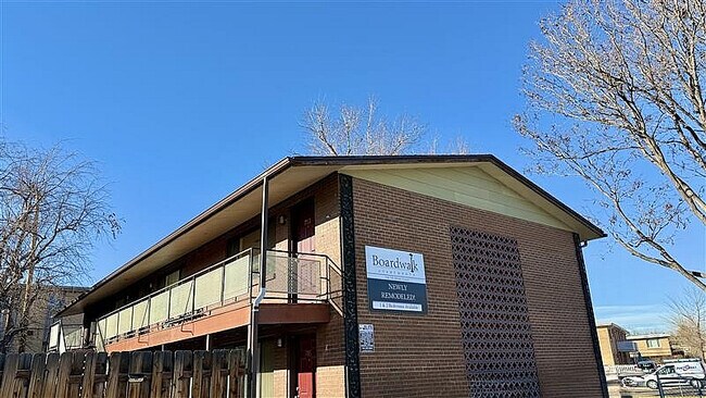 Charming newly remodeled brick apartment building with modern balcony and clear skies. - Boardwalk Apartments