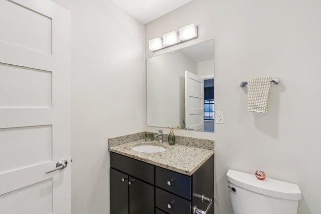 Baño moderno en apartamento con tocador con espacio de almacenamiento y accesorios actualizados.