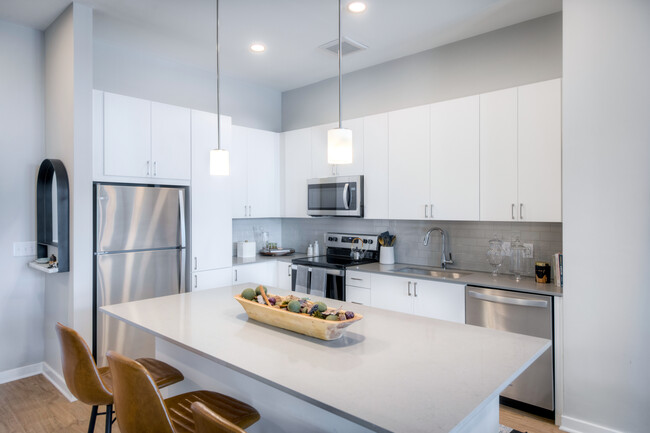 Scheme 1 kitchen with quartz countertops, tile backsplash, stainless steel appliances and hard surface flooring - Avalon Towson Apartments